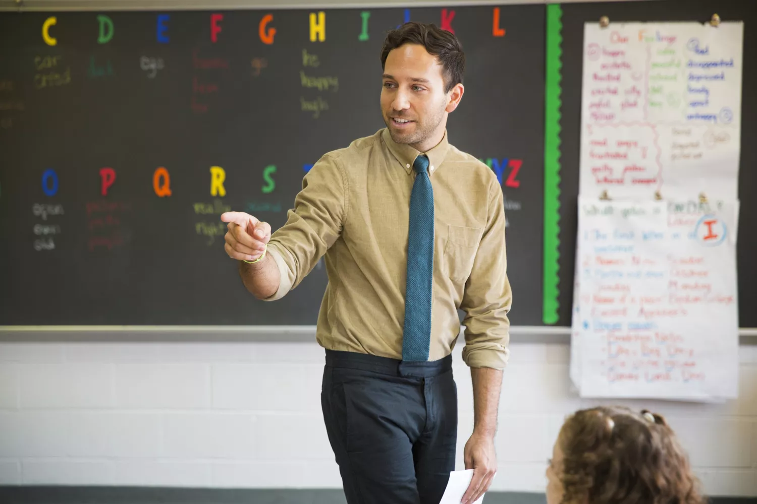 Male teacher pointing while teaching in elementary classroom