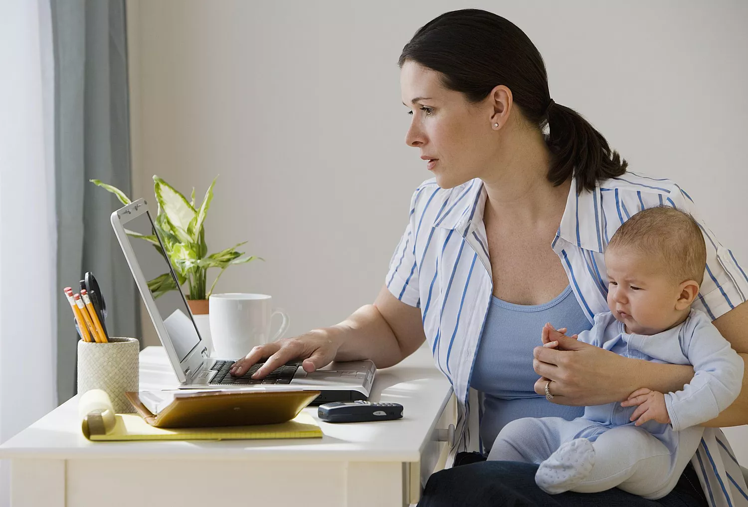 woman working on laptop with baby in her lap
